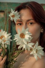 Close up portrait of young woman with bouquet of daisies outdoors