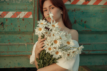 a young girl in a beautiful beige dress with flowers near the cart. film and grain effect