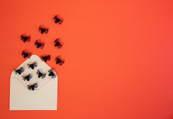 Spooky flat lay with spiders and house-shaped blank paper on orange backdrop. Perfect for Halloween design and seasonal concepts. 