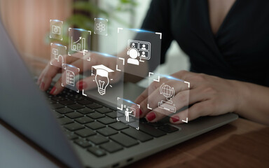 Hands on a laptop keyboard with holographic icons of education, online learning, video conferencing, research, and innovation. Concept of digital transformation in e-learning and knowledge sharing.