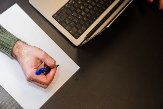 concetti sul lavoro in ufficio, stare seduti alla scrivania, utilizzare un computer e prendere appunti con carta e penna