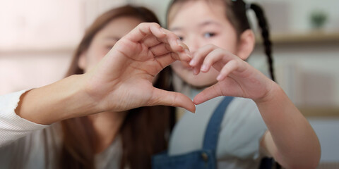 Mother and daughter forming a heart shape with hands, expressing love