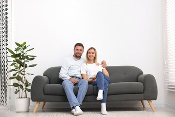 Obraz premium Couple with air conditioner remote control on sofa at home