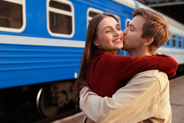 Goodbye. Lovely couple hugging near train outdoors, space for text