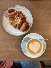 Cinnamon roll croissant and coffee cappucino on wooden table