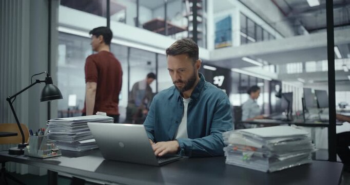 Caucasian Man Experiencing Pressure with Workload while Working with Documents in Office on His Laptop Computer. Manager is Stressed and Finds it Hard to Concentrate on a Project