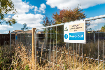 Shallow focus of a Keep Put sign seen attached to a metal fence at the perimeter of a new housing development site in the UK. The fence runs next to a public footpath.