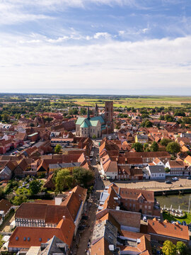 Aerial view of the majestic Ribe Cathedral rising above a sea of terracotta rooftops, its spires piercing the blue sky, Ribe, Denmark.