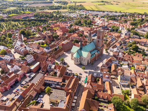 Aerial view of Ribe Cathedral's green roof contrasts with the red rooftops of the surrounding buildings, creating a vibrant tapestry of urban life, Ribe, Denmark.