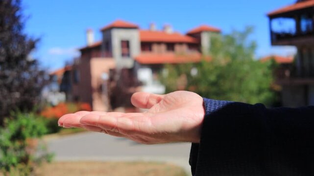 The owner of an apartment or house hands over the keys to a new tenant or buyer. A profitable house sale deal. A silver house-shaped keychain. Selling and buying a house.