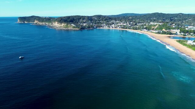 Drone aerial landscape of ocean waves swell with seaside coastal town in the background of Avoca Beach suburbs bushland coastline headland bay Central Coast Australia tourism travel nature outdoors
