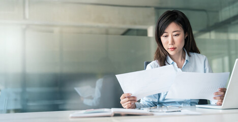 Banner of asian young business woman working on laptop computer reading financial document in office. Accountant entrepreneur, banker manager businesswoman doing report paperwork using pc. Copy space