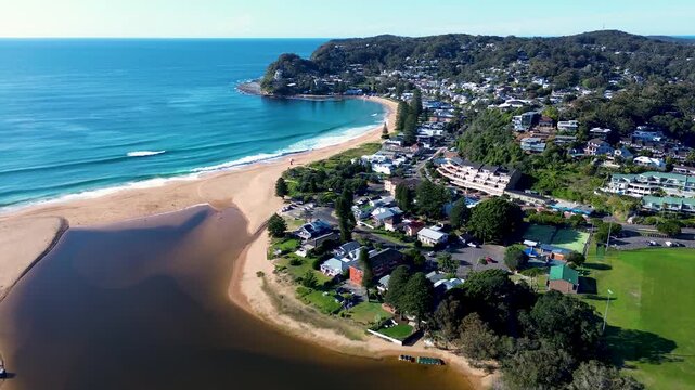 Drone aerial landscape of ocean waves breaking on Avoca Beach town with residential housing coastal lagoon coastline and bushland headland in Central Coast Australia travel tourism nature outdoors