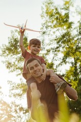 Excited young boy midair, smiling joyfully while being tossed up by a parent on a sunny day with...