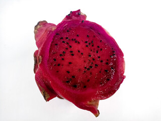 A close-up of a half dragon fruit shows the vibrant pink flesh with small black seeds. Isolated against a white background, it showcases the fruit's texture and color