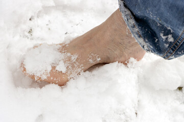 A closeup of a bare foot stepping in fresh snow