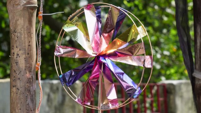 Colorful metallic pinwheel spinning outdoors on sunny day