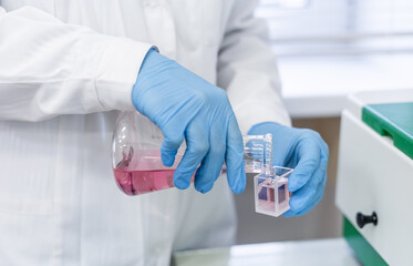 A woman in a medical laboratory performs a chemical test by placing a cuvette with liquid into a spectrophotometer to subsequently determine the concentration of the solution