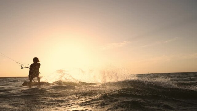 Slow motion kitesurfer jumping high above waves at golden hour sunset showing extreme water sport energy adrenaline freedom lifestyle and breathtaking dynamic ocean adventure performance