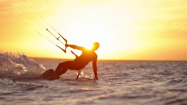 Dynamic kitesurfer flying over ocean waves at sunset golden hour creating splash symbol of freedom inspiration lifestyle adventure tropical holiday paradise commercial vacation summer vibes