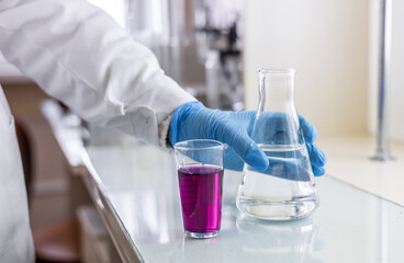 Chemistry laboratory glassware with color liquids. Laboratory analysis. Glassware with different liquids on white table indoors, closeup.