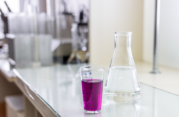 Chemistry laboratory glassware with color liquids. Laboratory analysis. Glassware with different liquids on white table indoors, closeup.