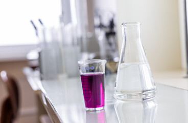 Chemistry laboratory glassware with color liquids. Laboratory analysis. Glassware with different liquids on white table indoors, closeup.