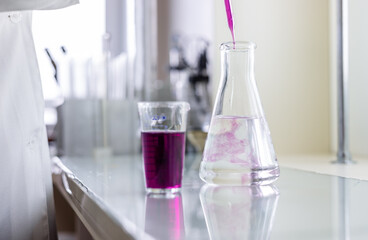 Chemistry laboratory glassware with color liquids. Laboratory analysis. Glassware with different liquids on white table indoors, closeup.