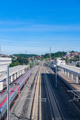 Naklejka premium Modern high-speed railway station in Padalarang, Bandung, Indonesia, with multiple tracks stretching into the horizon under bright blue skies, showcasing transportation progress.