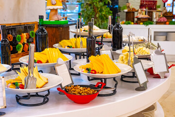 Food Still Life - Variety of Aged Cheeses Spread Out white Table in front of Black Background with Copy Space. Luxury hotel open buffet, wide variety of cheeses