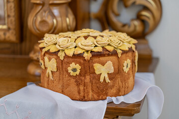 Traditional Ukrainian wedding bread korovai decorated with dough flowers and bows, symbolizing prosperity and unity, served on an embroidered ritual towel