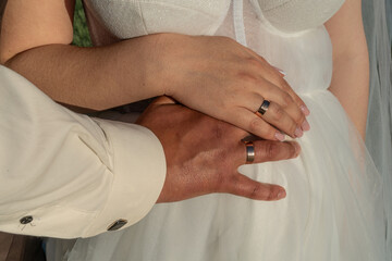 bride and groom holding hands, close-up of wedding rings