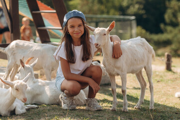 Little girl is on the goat farm outdoors at daytime