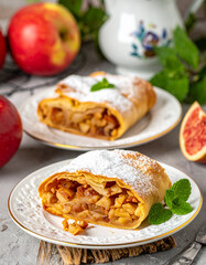A crispy Oktoberfest apple strudel topped with powdered sugar served on decorative porcelain dishes.