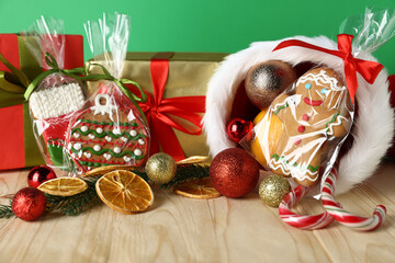Happy Saint Nicholas day. Different festive decor, gift boxes and cookies on wooden table against green background, closeup