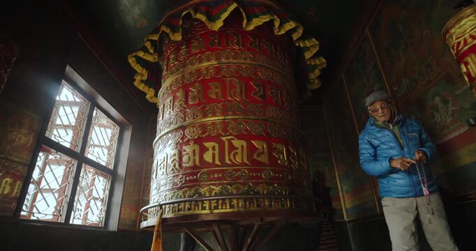 Tourists and locals rotate big prayer wheel at Boudha Stupa, Kathmandu, Nepal. A Buddhist monument where prayers meditation reflect culture, belief, and spiritual tourism in a sacred heritage setting
