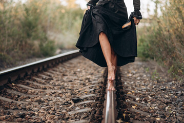 Barefoot Woman Balances on Railway Track in Black Dress