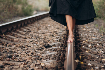 Barefoot Woman Balances on Railway Track in Black Dress