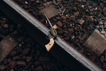 Antique Revolver on Train Track Rails Surrounded by Rocks