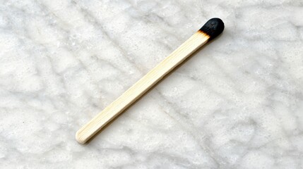 A burnt matchstick on a marble surface.