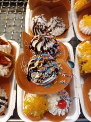 Khanom Bueang is a Thai snack that has been adapted to the times by adding whipped cream.