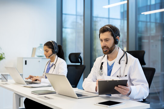 Medical professionals wearing headsets and lab coats, sitting at desks with laptops, are providing remote online healthcare consultation services in a modern office helping patients