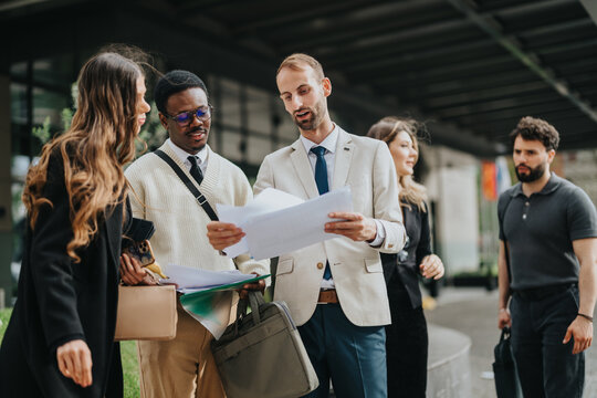 Team of business professionals having a discussion outside, reviewing documents and collaborating effectively.