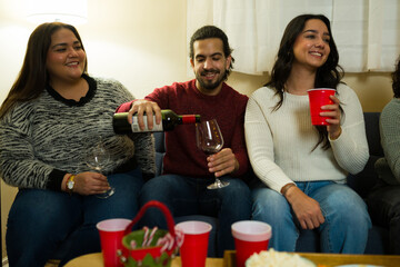 Man celebrating christmas holidays with friends and pouring red wine