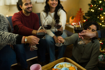 Closeup of a group of friends toasting red wine celebrating christmas reunion
