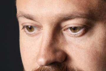 Man with beautiful eyes on black background, closeup