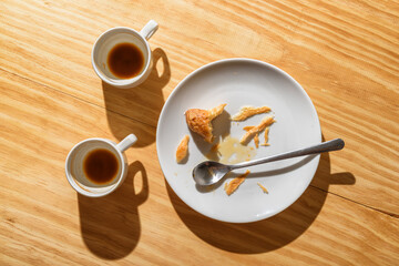 Empty espresso cups and croissant crumbs on white plate