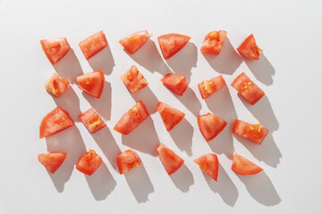 Rows of red tomato chunks on white background. Top view