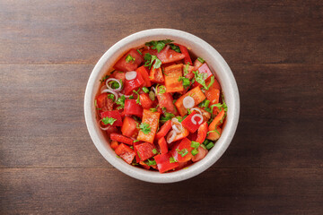 Top view of fresh red vegetable bowl on wooden table