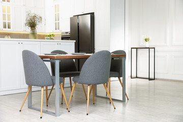 Kitchen interior with dining table, place setting and grey chairs